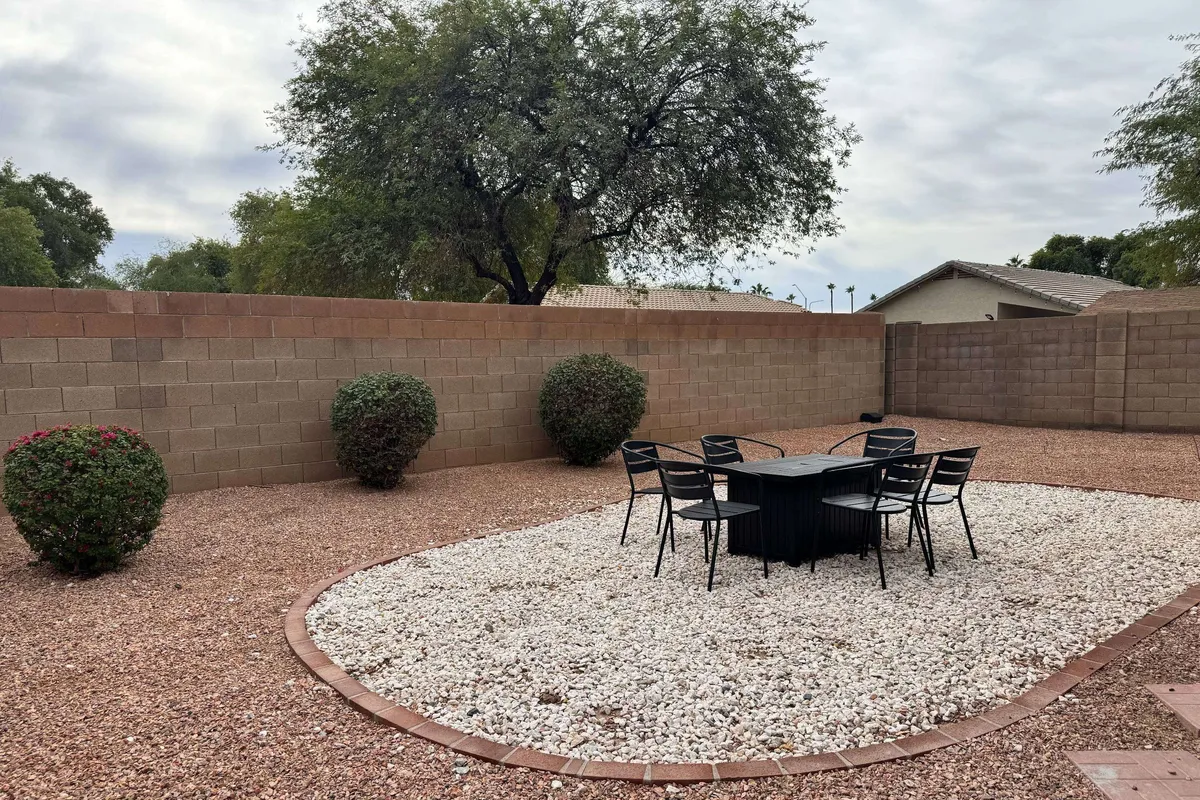 This exterior image features a dining table and chairs arranged on a landscaped patio area surrounded by a stone wall. The inviting setup is ideal for family meals, starlit conversations, and festive gatherings, echoing the section’s focus on outdoor enjoyment.