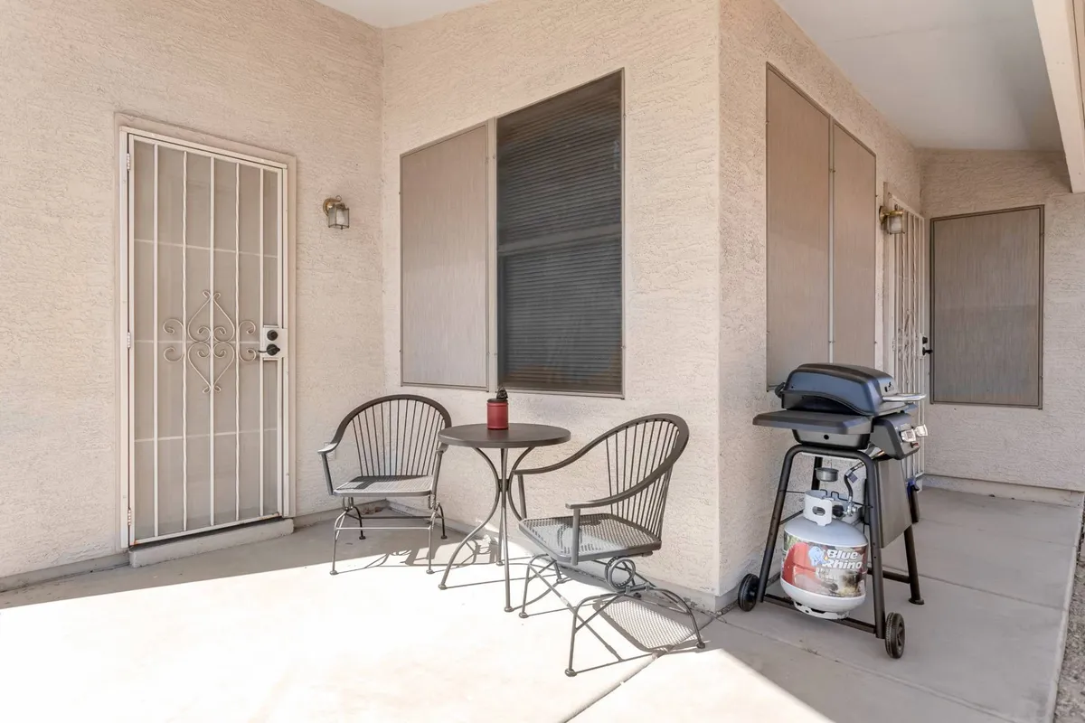 This image showcases an exterior space with a table and chairs, a BBQ grill, and the front door visible in the background. The setup invites outdoor dining and socializing, and the presence of the grill connects directly to the description of backyard barbecues and gatherings.