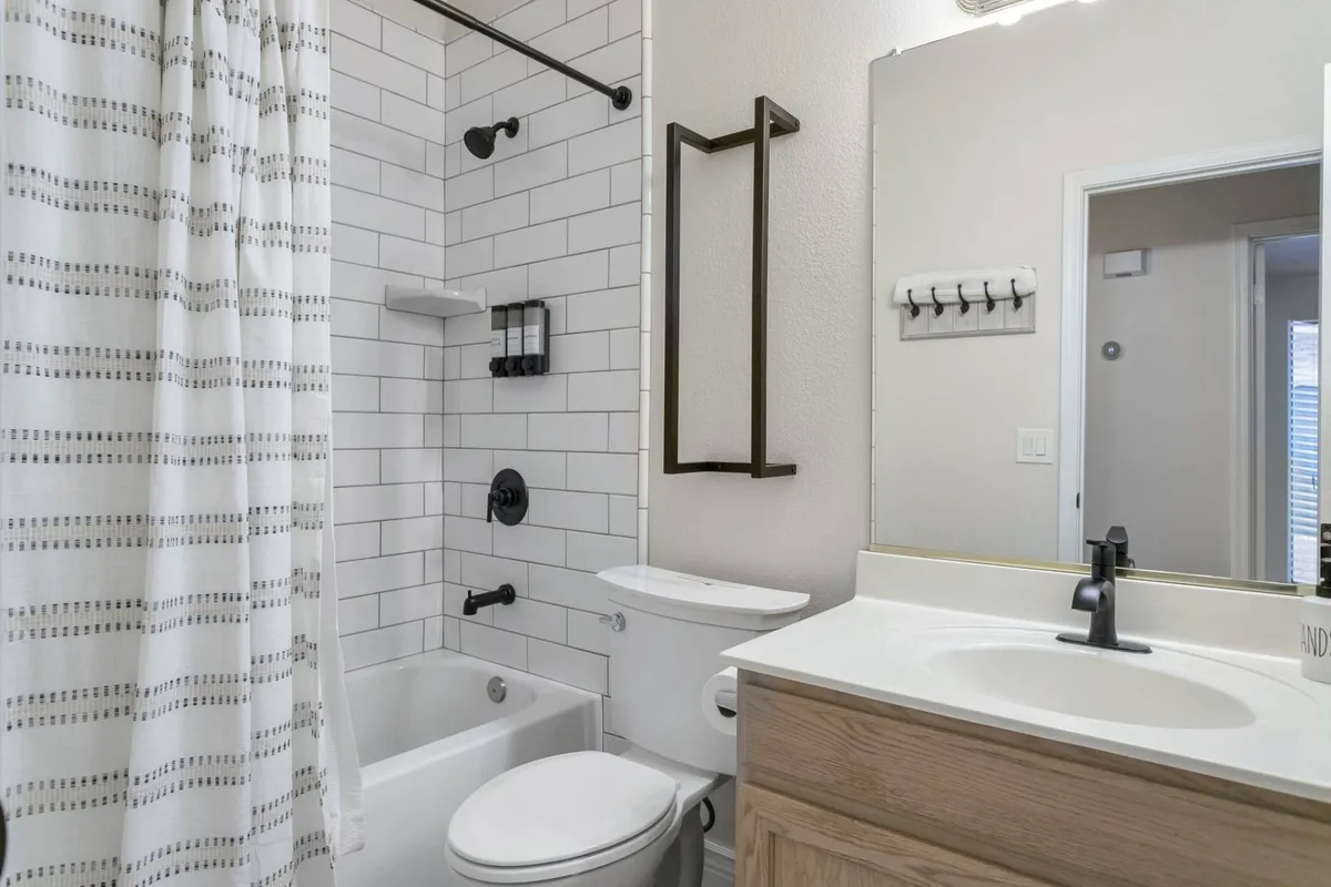 A clean and modern bathroom with a standalone bathtub, sink, and large mirror. The bright, airy space is designed for relaxation and refreshing routines.